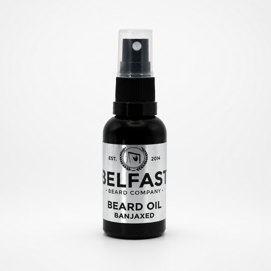 A bottle of Belfast Beard Company Beard Oil in the 'Banjaxed' scent, featuring a black bottle and a white label with black text, set against a plain white background.